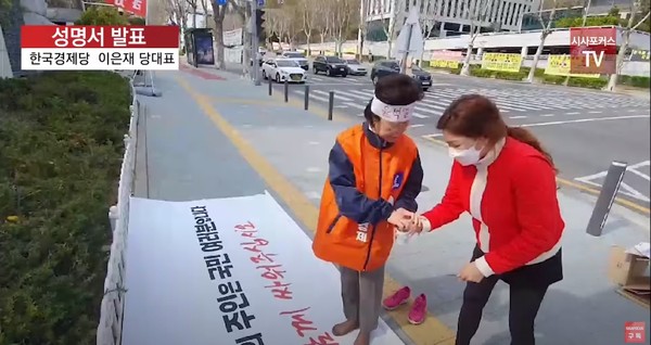 이은재 의원이 수행하는 여성이 가져온 종이컵에 손가락을 담그고 있다. 시사포커스TV 유튜브 화면 캡처.