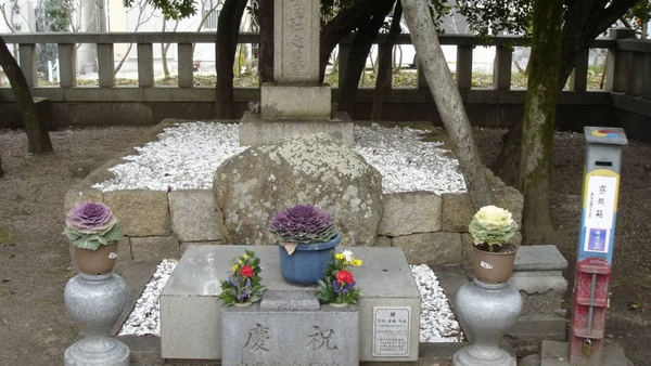 그림 1. 왕인의 무덤으로 전해지는 작은 바위. 뒤에 서 있는 ‘박사왕인지묘’ 비석은 후대에 세워진 것이다.